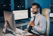 Young man looking at computer with trading graph