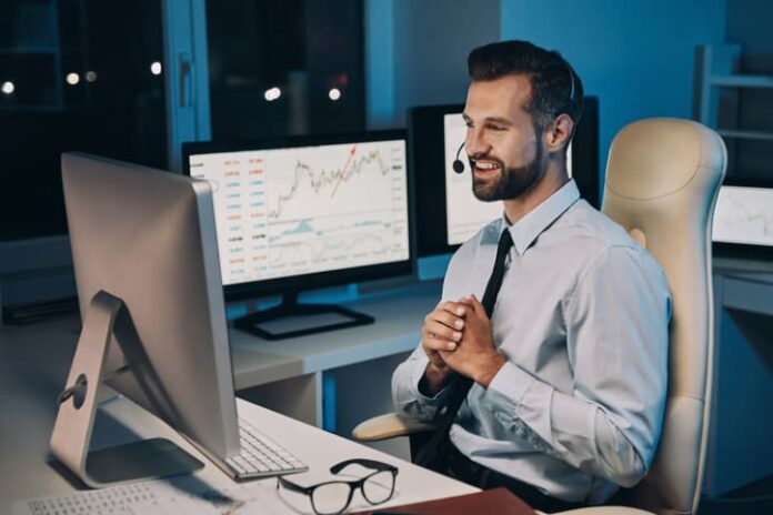 Young man looking at computer with trading graph