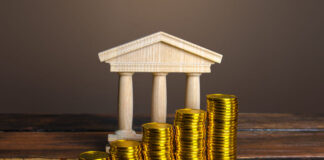 Bank building and increasing stacks of coins