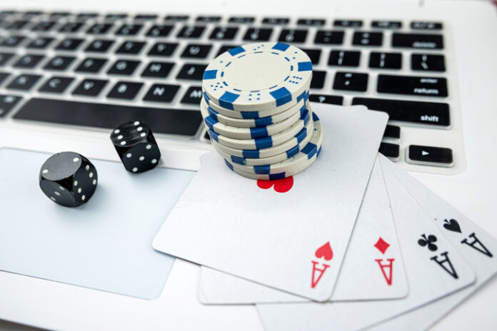 Business online poker games with laptop two black dice playing card and casino chips.