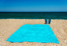 Blue sandal flip flop and towel on yellow sand