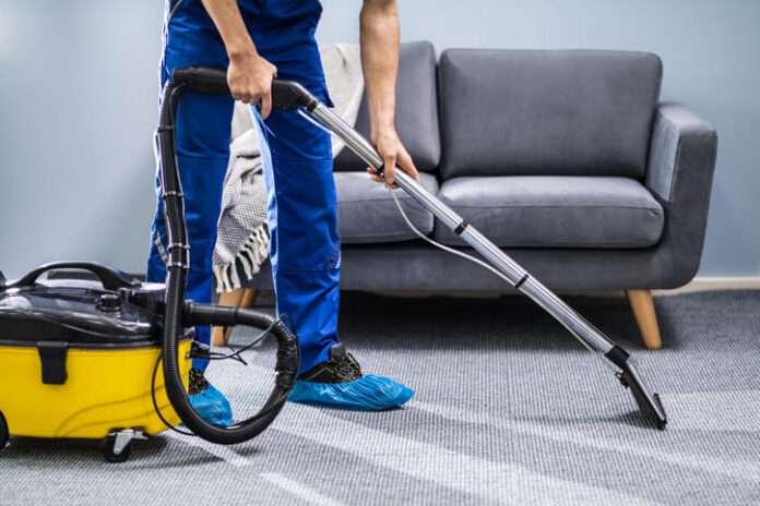 Person Cleaning Carpet With Vacuum Cleaner