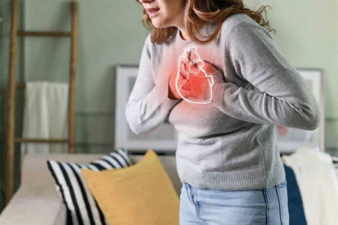 Young woman pressing on chest with painful expression