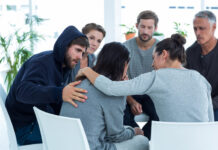 Concerned patients comforting another in rehab group at a therapy session