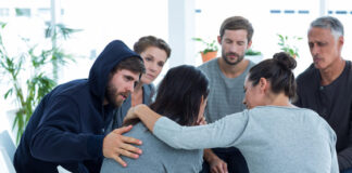 Concerned patients comforting another in rehab group at a therapy session