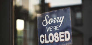 Closeup shot of a sign that says "Sorry We're Closed" hanging on a glass door