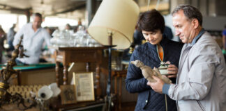 Cheerful mature spouses buying retro handicrafts on flea market