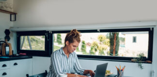 Young businesswoman working at home with laptop and papers on desk in the kitchen