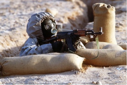 A syrian soldier in a foxhole aiming an AK47