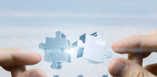 Hands putting puzzle piece together on bright city background