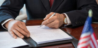 Hands of mature American delegate in formalwear pointing at signature