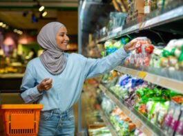 Joyful smiling Arab woman in a hijab chooses products in a supermarket