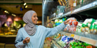 Joyful smiling Arab woman in a hijab chooses products in a supermarket