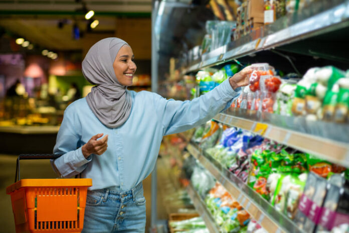 Joyful smiling Arab woman in a hijab chooses products in a supermarket