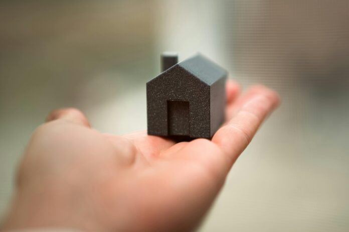 pexels-jakubzerdzicki-29091316 Hand holding small house