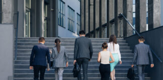Business People Walking up the Stairs. Men and women in formal suits going up stairs into office building.
