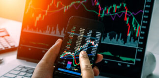 Businessman checking stock market by his smartphone and labtop.
