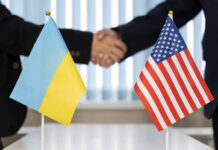 Political flags of Ukraine and United States of America on table in international negotiation room