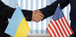 Political flags of Ukraine and United States of America on table in international negotiation room