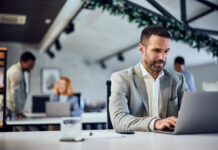 An elegantly dressed man working in the co-working space, using a laptop
