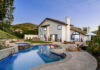 Modern luxury house with a swimming pool and patio area, surrounded by greenery and a clear evening sky.