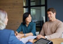 Young mixed race couple discussing financial plans with advisor.