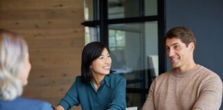 Young mixed race couple discussing financial plans with advisor.