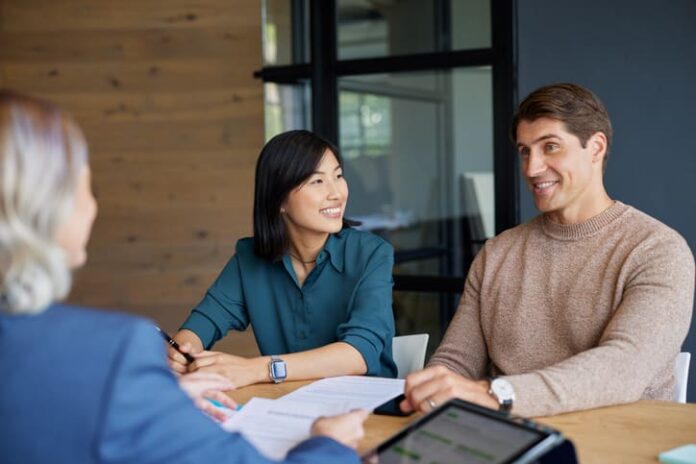 Young mixed race couple discussing financial plans with advisor.