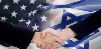 Two businesspeople shaking hands after good deal in front of the the american and israel flags