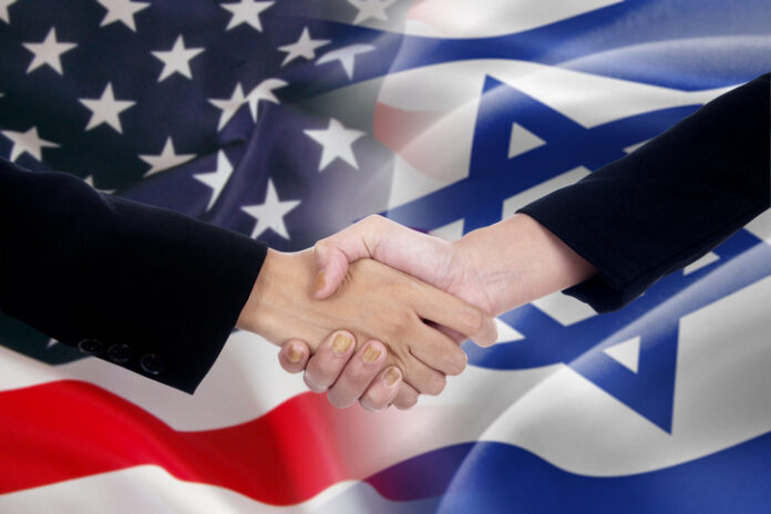 Two businesspeople shaking hands after good deal in front of the the american and israel flags
