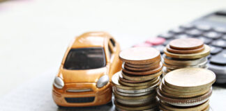 Miniature car model, coins stack, calculator and saving account book or financial statement on office desk table