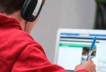boy working on school work with laptop and headphones