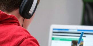boy working on school work with laptop and headphones
