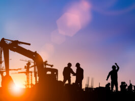 Silhouette of engineer and construction team working at site over blurred background for industry background with Light fair.