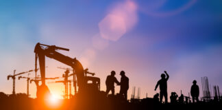 Silhouette of engineer and construction team working at site over blurred background for industry background with Light fair.