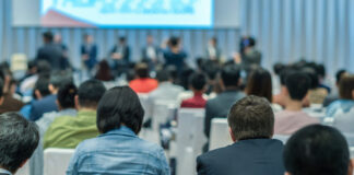 Speakers on the stage with Rear view of Audience in the conference hall