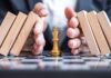 Business man hand protect Chess King figure and Stopping Falling wooden Blocks or Dominoes. Business, Risk Management, Solution, economic regression,