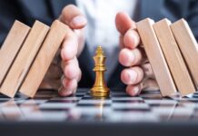 Business man hand protect Chess King figure and Stopping Falling wooden Blocks or Dominoes. Business, Risk Management, Solution, economic regression,