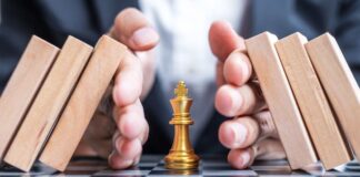 Business man hand protect Chess King figure and Stopping Falling wooden Blocks or Dominoes. Business, Risk Management, Solution, economic regression,