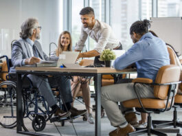 Selective focus of smiling disabled businessman and colleagues in office.