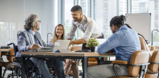 Selective focus of smiling disabled businessman and colleagues in office.