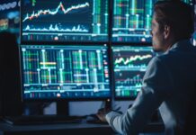 Trader analyzing stock charts on screens
