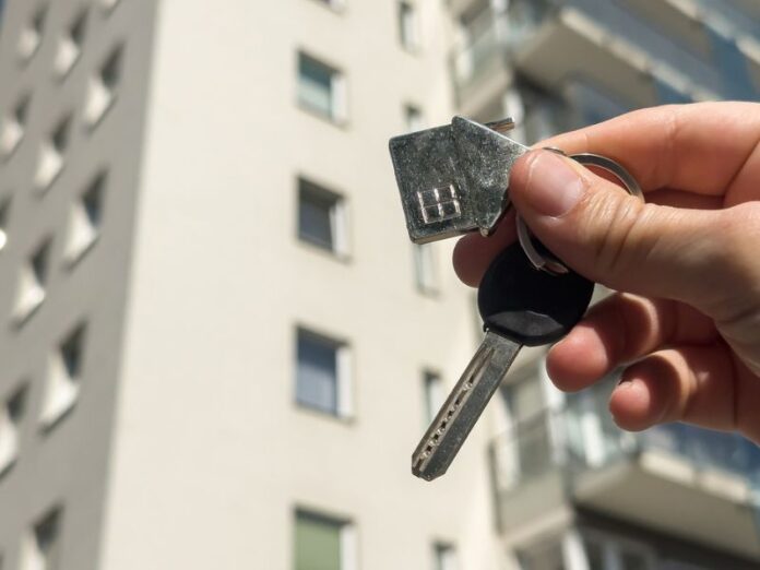 Woman holds key against a multi-storey residential area