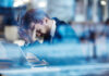 Tired employee holding his head in hands and leaning over laptop