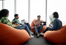 Male with AI project on laptop chatting with teammates