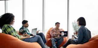 Male with AI project on laptop chatting with teammates