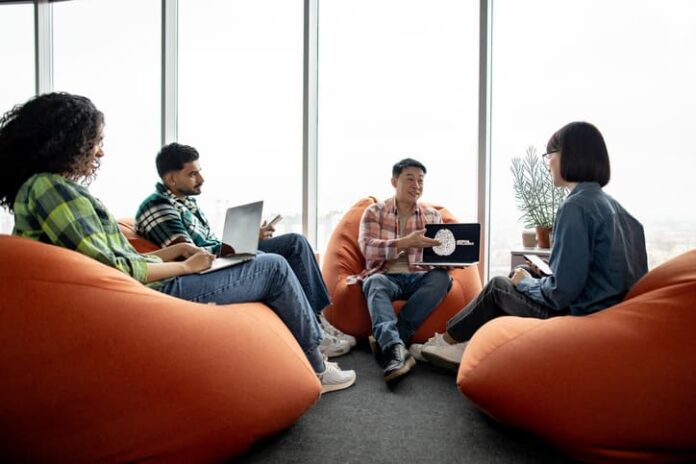 Male with AI project on laptop chatting with teammates