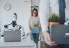 Dismissed business people packing their belongings and leaving the office, a robot is sitting at the desk and working