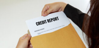 Cropped Hands Removing Credit Report From Envelope At Table