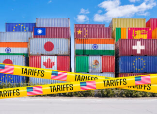 Shipping containers adorned with global flags, barricaded by US Tariffs tape
